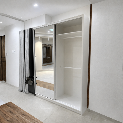 A modern white built-in wardrobe with mirrored sliding doors and open shelving, shown installed in a minimalist room with light gray walls and tiled flooring.